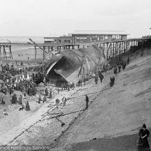 Crowds on beach in front of shipwreck
