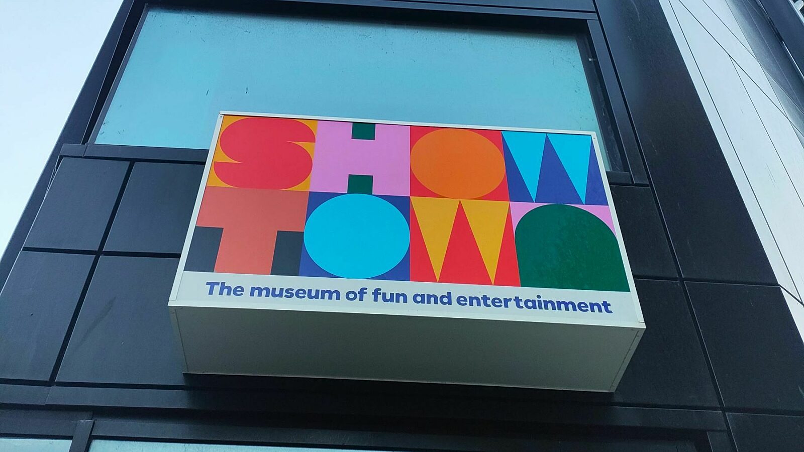 Image of the Showtown sign on the exterior of the museum, a black building with windows.