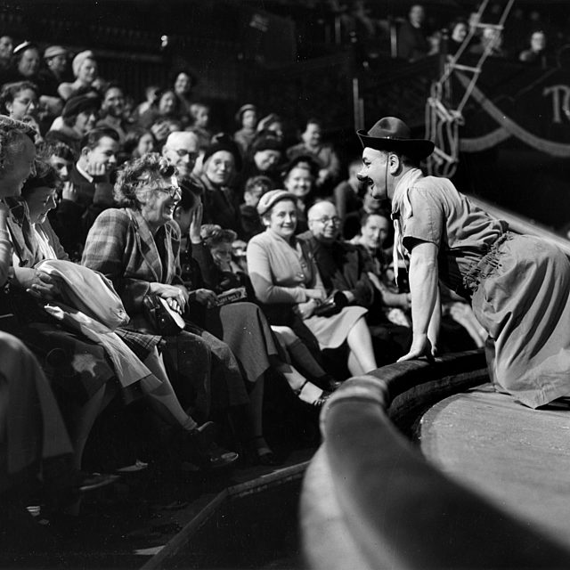 Black and white photograph of Clown, Charlie Cairoli leaning into the audience.